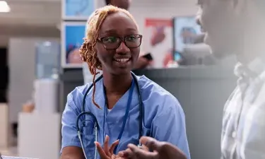 California medical assistant smiling and discussing treatment with patient in clinic