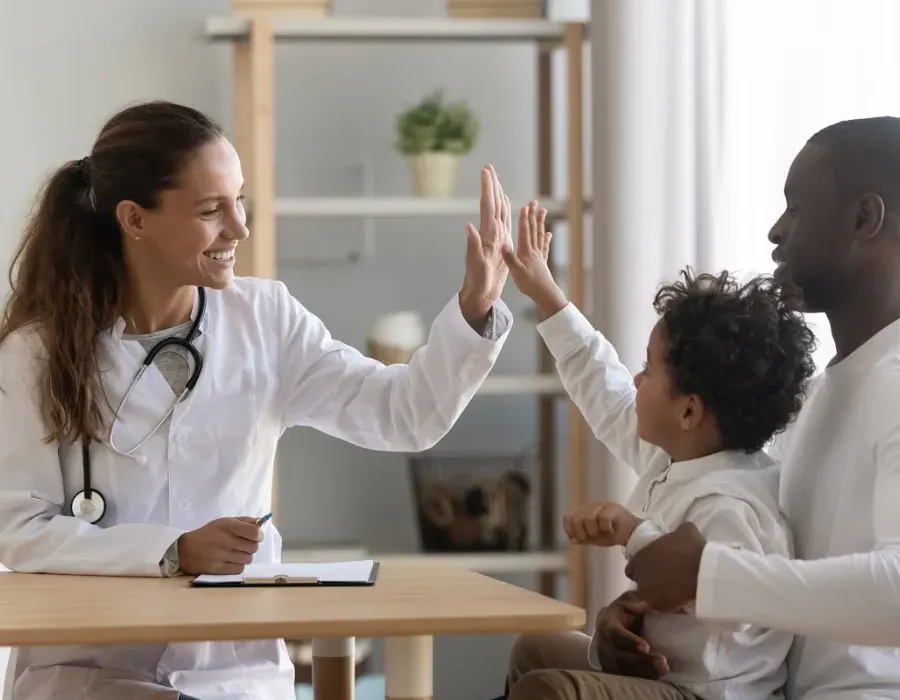 Family nurse practitioner high fiving pediatric patient in office during appointment