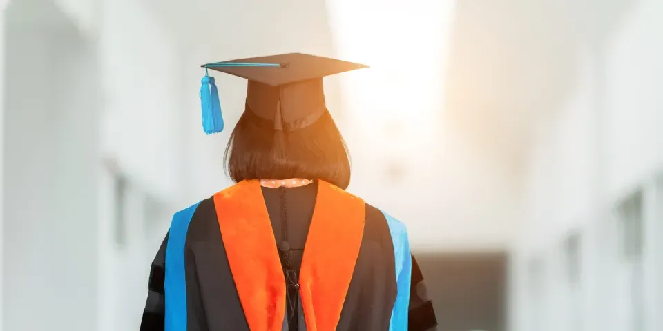 PhD student with their back facing viewer wearing an orange nursing hood